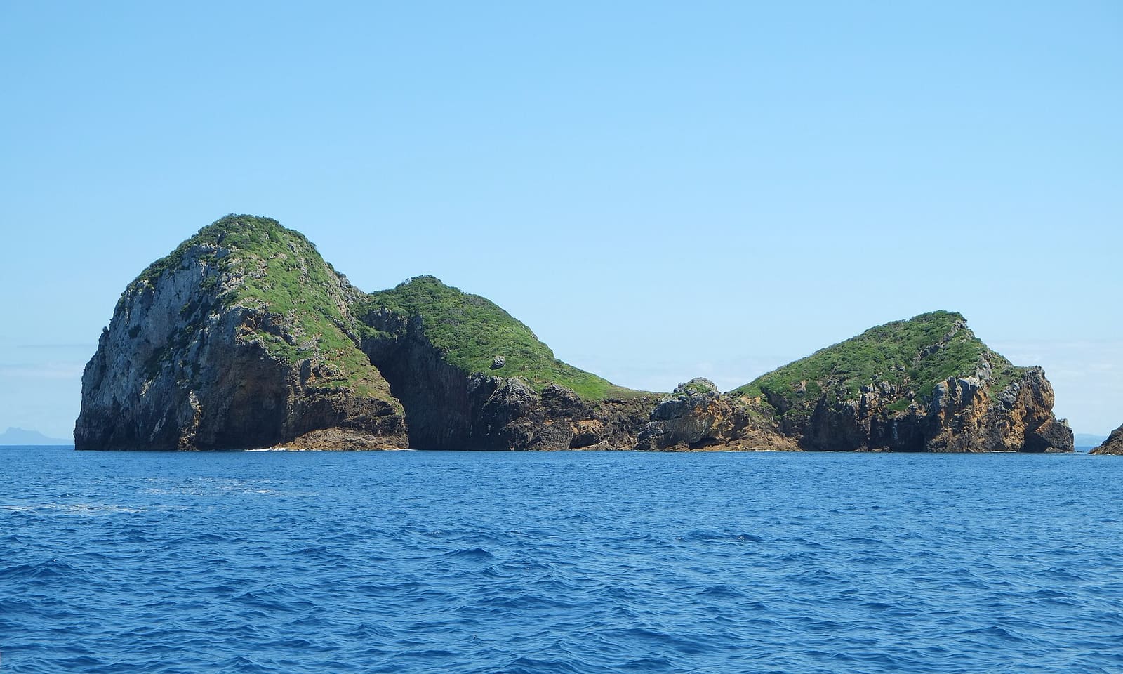 Archway Island south of Aorangi Island from northeast; the entrance to the tall rock arch (obscured) is discernible in the left part of the island